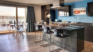 Een moderne keuken met een groot schiereiland, barstoelen en uitzicht op de jachthaven.