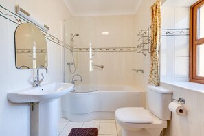 Une salle de bain équipée d’une douche, d’un lavabo, de toilettes et d’une fenêtre avec des rideaux.