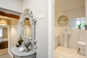 A bathroom with a sink, toilet, and a round mirror above the sink.