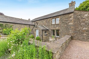 A stone house with a small garden, a white door, and a window.