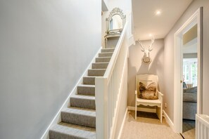 A staircase with patterned carpet, a white chair with a cushion, a wall-mounted mirror, and a deer head decoration. - 3 Bed in Barbon (oc-b33652) (Barbon)