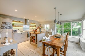 A modern kitchen with a central island, built-in appliances, and large windows offering a view of greenery. - 3 Bed in Barbon (oc-b33652) (Barbon)