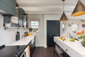 A modern kitchen with dark cabinetry, a marble countertop, and pendant lighting. - 2 Bed in Bamburgh (oc-586127) (Bamburgh)