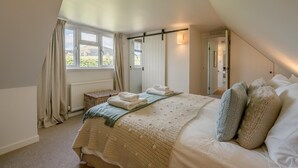Une chambre avec un grand lit, une fenêtre avec des rideaux, une table de chevet et une vue sur l’extérieur.