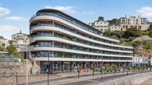 Ein mehrstöckiges Hotel mit geschwungener Fassade, Außenbereich und einer Steinmauer.