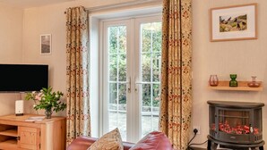 Una sala de estar con televisor, chimenea y ventana con cortinas.