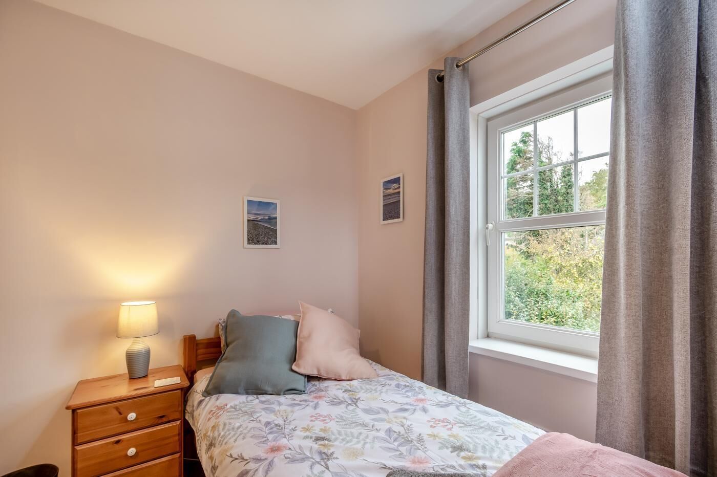 A bedroom with a bed, a bedside table with a lamp, and a window with curtains.