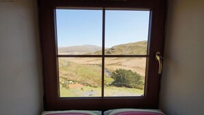 Een kamer met een raam dat uitkijkt op een landelijk landschap.