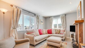 A cozy living room with a sectional sofa, a small armchair, and a TV stand. - 3 Bed in Seahouses (oc-566761) (Seahouses)
