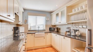 A modern kitchen with white cabinets, a granite countertop, a sink, a microwave, and a coffee maker. - 3 Bed in Seahouses (oc-566761) (Seahouses)