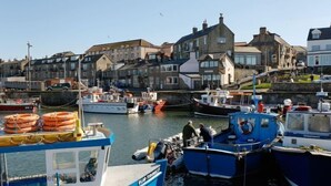 A harbor with boats docked, a building with a stone facade, and a clear sky. - 3 Bed in Seahouses (oc-566761) (Seahouses)
