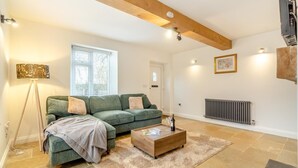Ein Wohnzimmer mit einem grünen Sofa, einem Holztisch und einer Heizung.