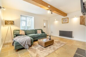 A living room with a green sofa, a wooden coffee table, and a radiator. - 2 Bed in Fincham (oc-t33561) (Fincham)