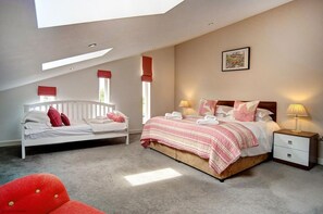 A bedroom with a skylight, two beds, a nightstand, and a red chair. - 4 Bed in Beadnell (oc-566397) (Beadnell)