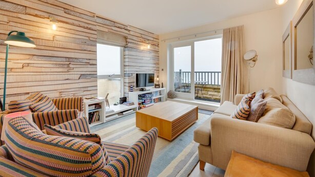 Ein modernes Wohnzimmer mit einer Holzwand, einem Sofa, einem Couchtisch und einem Fernseher.