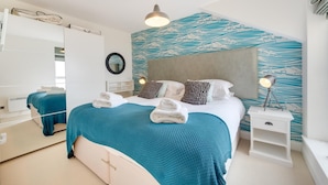 Ein modernes Schlafzimmer mit einem großen Bett, einem Nachttisch, einem Spiegel und einer Wand mit Wellenmuster.