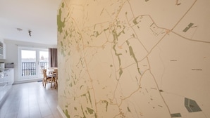 Ein geräumiges Zimmer mit einer großen Karte an der Wand, einem Essbereich mit Stühlen und Blick durch ein großes Fenster.