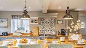 Una cocina moderna con una isla central, encimeras de madera e iluminación colgante.