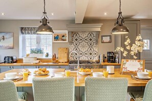 Une cuisine moderne dotée d’un îlot central, de plans de travail en bois et de luminaires suspendus.