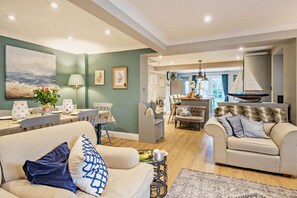 Un salon spacieux comprenant un canapé, des fauteuils et un coin repas avec une table et des chaises.