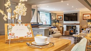 Un salón acogedor con chimenea, asientos cómodos, un televisor y un modelo decorativo de un velero.