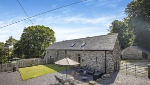 A stone building with a patio area, outdoor seating, and a fenced yard.