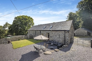 A stone building with a patio area, outdoor seating, and a fenced yard.