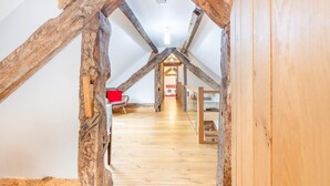 A loft-style room with exposed wooden beams, a wooden floor, and a red chair.