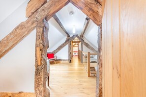 A loft-style room with exposed wooden beams, a wooden floor, and a red chair.