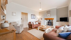 Una sala de estar acogedora con chimenea, televisor y una mesa de centro de madera.