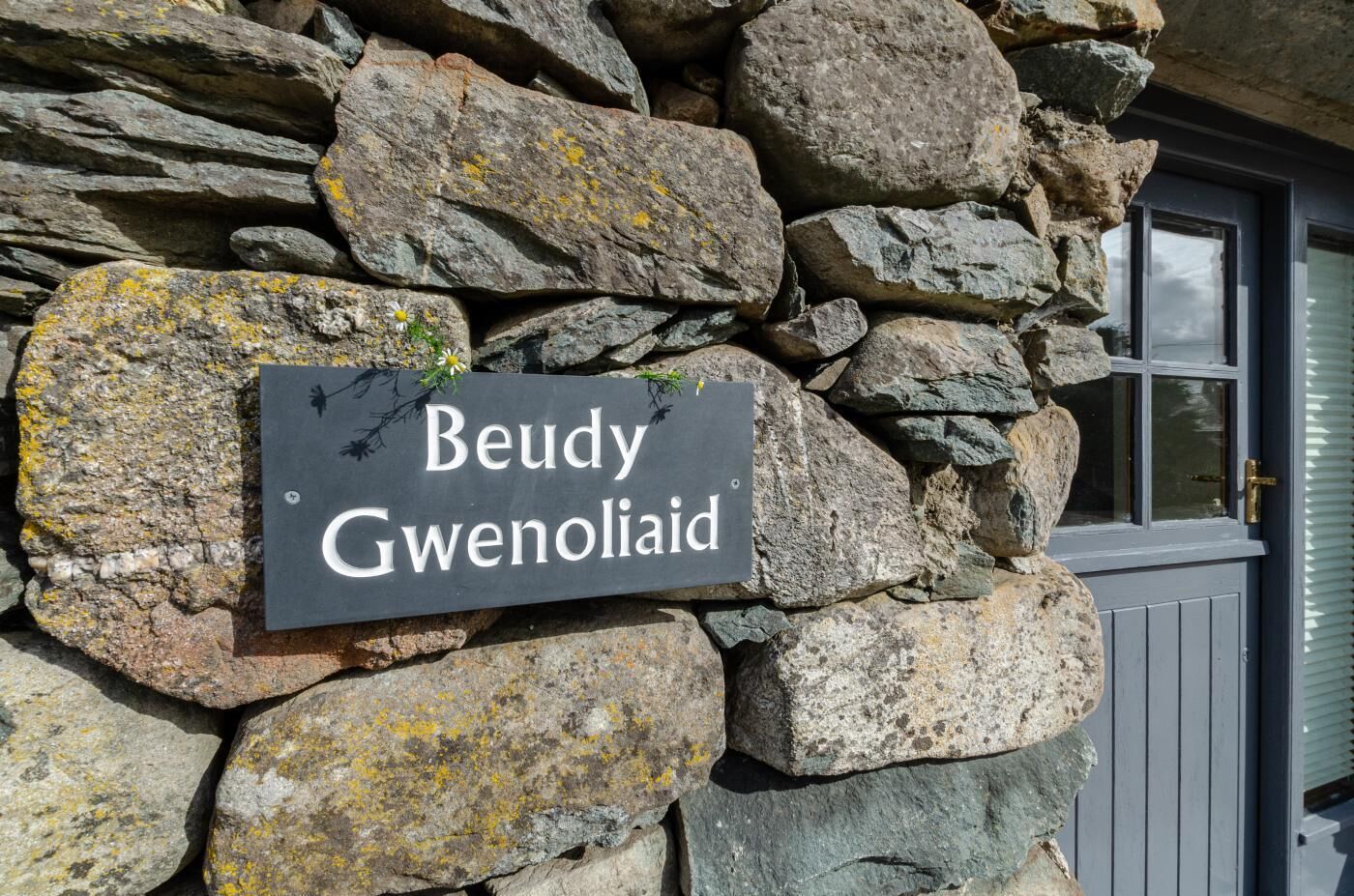 En stenvæg med et skilt, der står 'Beudy Gwenolaid'.