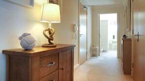 A hallway with a wooden cabinet, a lamp, and a decorative rope sculpture. - 2 Bed in Seahouses (oc-566411) (Seahouses)