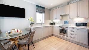 A modern kitchen with a dining area, featuring a flat-screen TV, a microwave, and a sink. - 2 Bed in Seahouses (oc-566411) (Seahouses)