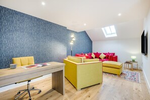 Un salon moderne avec un bureau en bois, un canapé jaune et un mur bleu à texture.