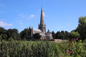 Une église historique, dotée d’un flèche imposante, entourée d’une végétation luxuriante et de plantes en fleurs.