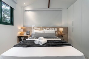 A modern hotel room with a neatly made bed, a bedside lamp, and a view of the outdoors through a window. - Lobie Vilares Copacabana (Rio de Janeiro)