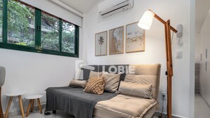 A modern living room with a sofa, a standing floor lamp, and a window with a view of greenery. - Lobie Vilares Copacabana (Rio de Janeiro)
