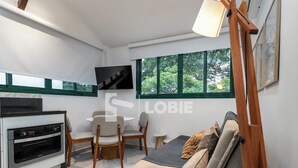 A modern living room with a sofa, a small table, and a TV mounted on the wall. - Lobie Vilares Copacabana (Rio de Janeiro)