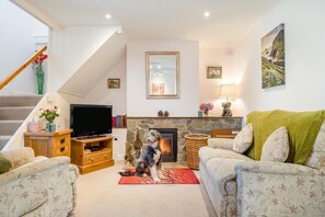 A living room with a fireplace, a television, and a dog.