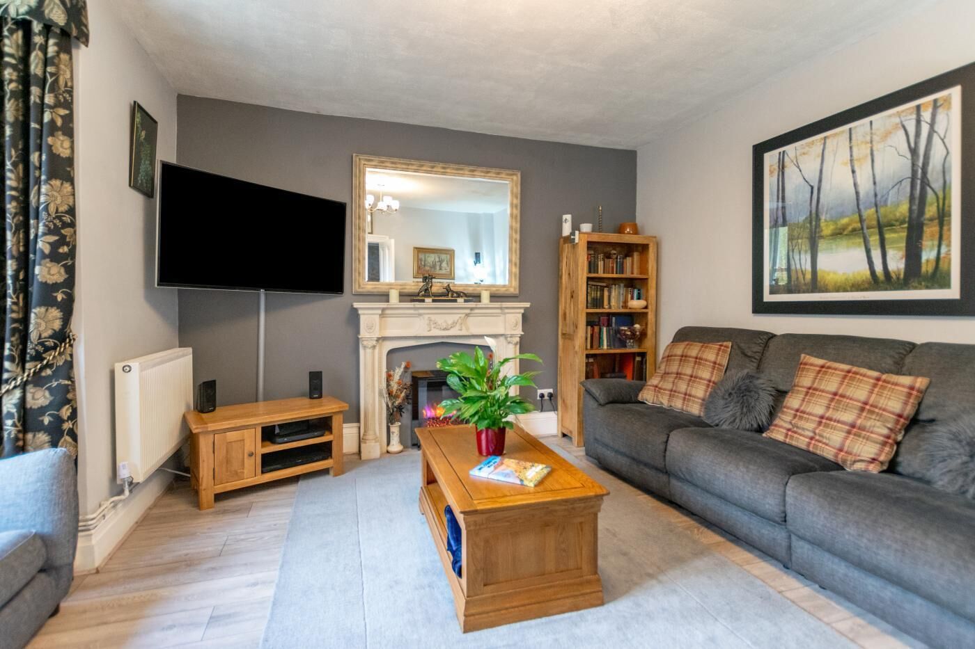 A living room with a fireplace, a television, a bookshelf, and a sofa.