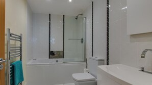 Een moderne badkamer met een bad, toilet en wastafel.