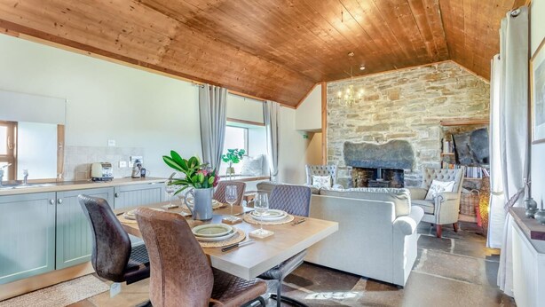 A modern kitchen with a dining area, stone fireplace, and wooden ceiling. - 1 Bed in Wick (oc-b33442) (Wick)
