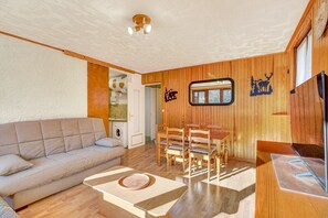Un salon comprenant un canapé, une table à manger, des chaises et un téléviseur.
