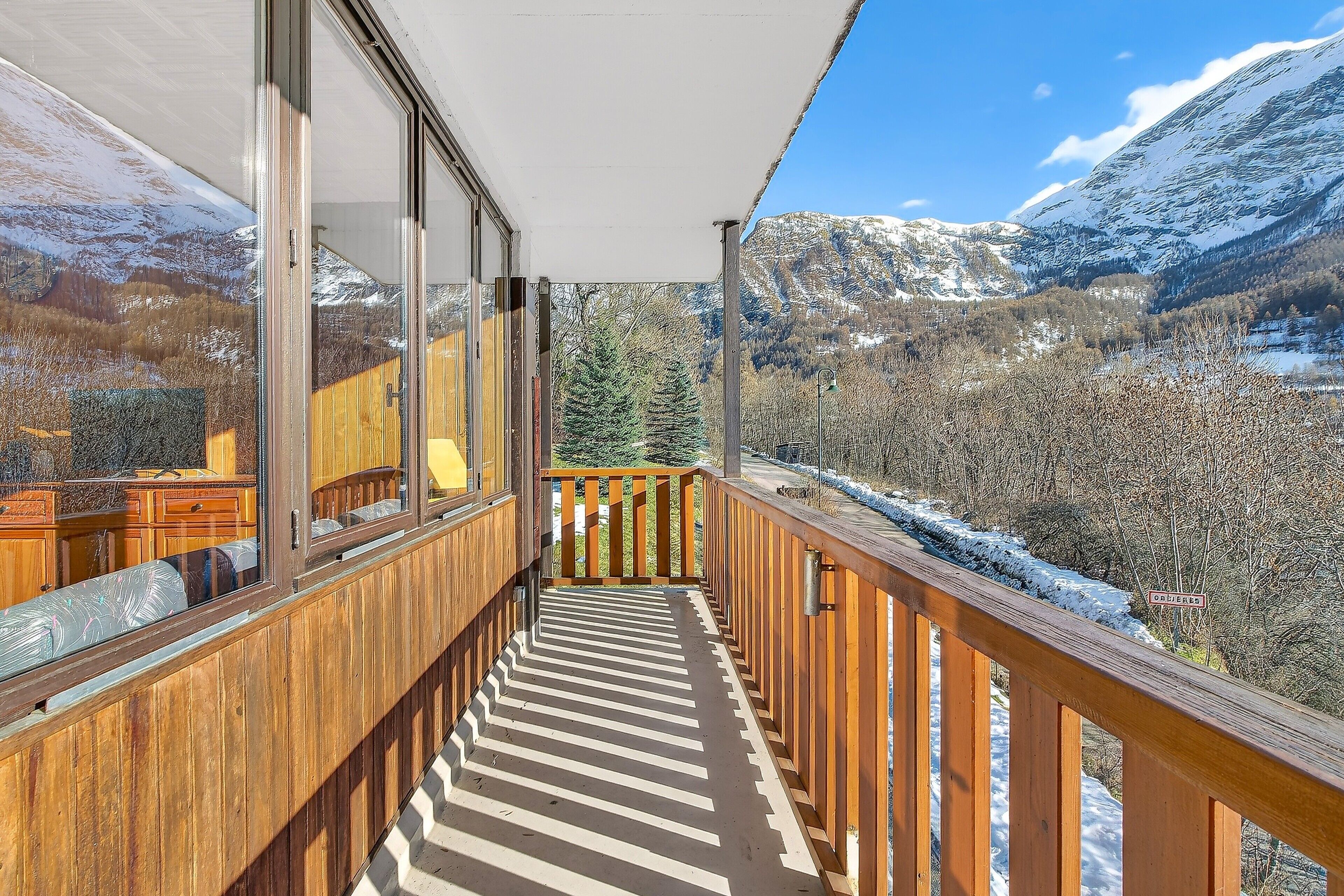 Ein hölzerner Balkon mit Blick auf schneebedeckte Berge und einen klaren Himmel.