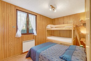 A room with wooden walls, a bunk bed, a window with curtains, a radiator, and a bedside lamp. - Apartment 'Orcières Village' with Mountain View and Balcony (Orcières)