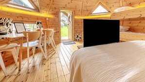A cozy wooden cabin with a dining area, a bed, and a large window. - 1 Bed in Redberth (oc-h33668) (Redberth)
