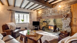 A cozy living room with a stone fireplace, leather sofas, a wooden coffee table, and a television. - 3 Bed in Cwmystradllyn (oc-wag708) (Cwmystradllyn)