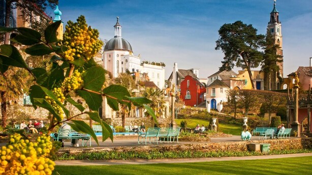 A park with benches, a fountain, and historic buildings including a church with a dome and a tower. - 3 Bed in Cwmystradllyn (oc-wag708) (Cwmystradllyn)