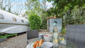 A table set outdoors with a croissant, a bottle of sparkling wine, and glasses.