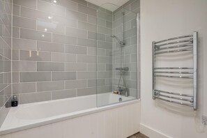 A modern bathroom with a glass-enclosed shower, a white bathtub, and a chrome towel rack. - 2 Bed in Bamburgh (oc-nb1969) (Bamburgh)